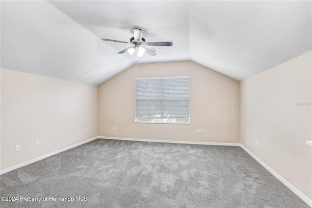 additional living space featuring a textured ceiling, light colored carpet, vaulted ceiling, and ceiling fan