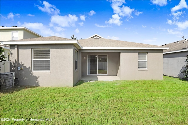 back of property with central AC and a lawn