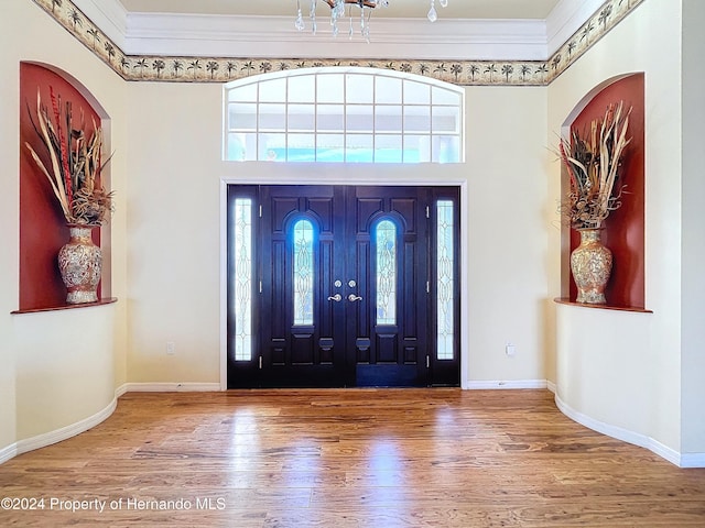 foyer with wood-type flooring, crown molding, and a high ceiling