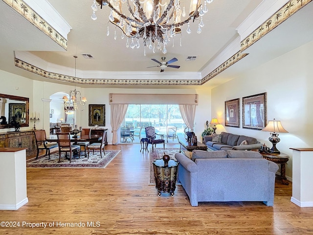 living room featuring hardwood / wood-style floors, ceiling fan with notable chandelier, and crown molding