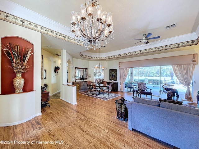 living room featuring ceiling fan with notable chandelier, wood-type flooring, and ornamental molding