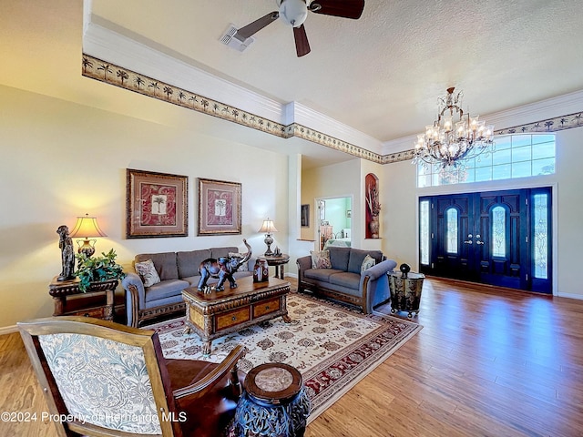 living room featuring ceiling fan with notable chandelier, a textured ceiling, and hardwood / wood-style flooring