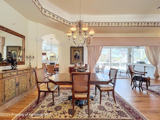 dining room featuring light wood-type flooring, ornamental molding, and an inviting chandelier