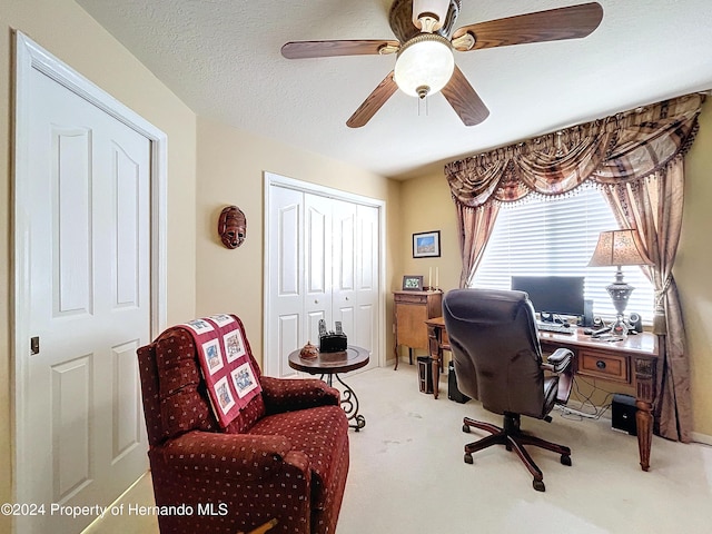 carpeted home office with a textured ceiling and ceiling fan