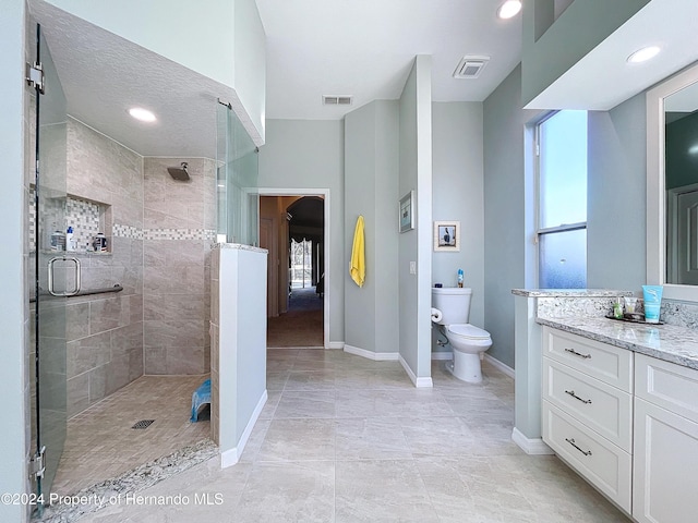 bathroom featuring tile patterned floors, vanity, a textured ceiling, a shower with door, and toilet