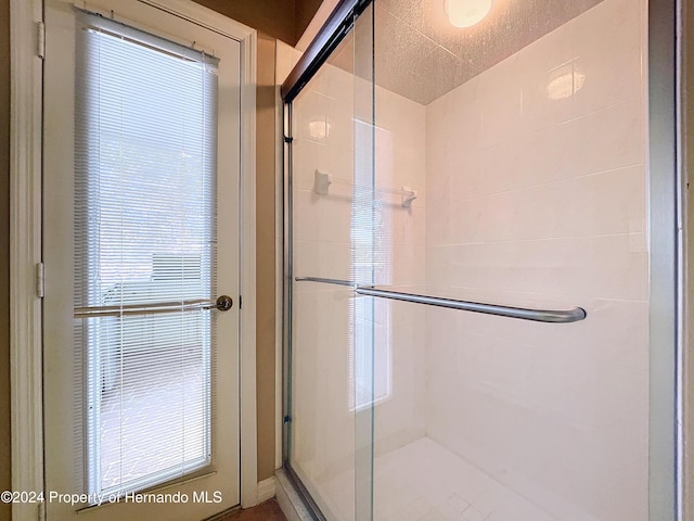 bathroom featuring a shower with shower door and a textured ceiling