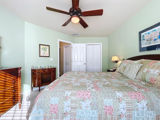 bedroom with a textured ceiling, ceiling fan, light carpet, and a closet