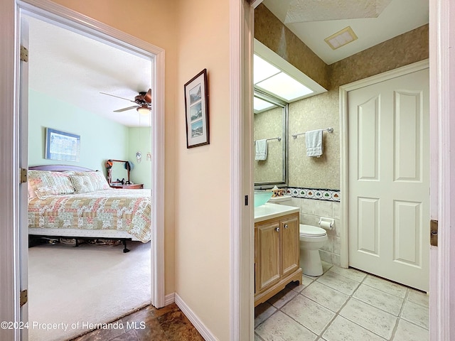 bathroom featuring tile patterned floors, vanity, ceiling fan, tile walls, and toilet