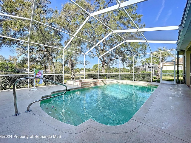 view of swimming pool featuring glass enclosure, a jacuzzi, and a patio