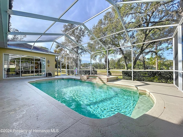 view of pool with glass enclosure and a patio