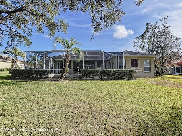 view of front of home with glass enclosure and a front lawn