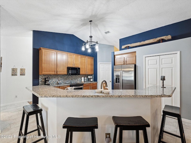 kitchen featuring a breakfast bar, lofted ceiling, sink, hanging light fixtures, and appliances with stainless steel finishes