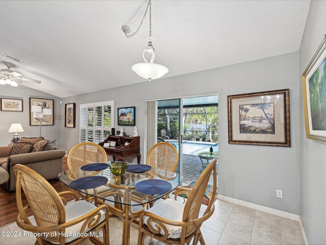 tiled dining room with a textured ceiling, plenty of natural light, lofted ceiling, and ceiling fan