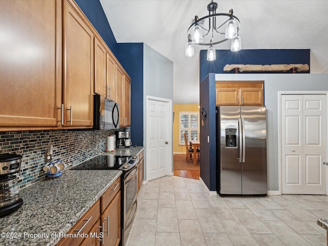 kitchen featuring hanging light fixtures, an inviting chandelier, dark stone countertops, a textured ceiling, and appliances with stainless steel finishes