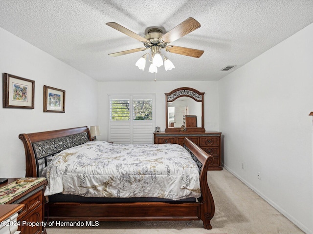 bedroom featuring ceiling fan, a textured ceiling, and light carpet