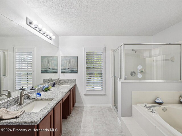 92 Randolph Ave, Spring Hill, FL 34606 - full bathroom featuring a textured ceiling, a garden tub, double vanity, a stall shower, and plenty of natural light