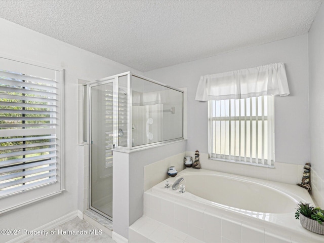 bathroom with shower with separate bathtub and a textured ceiling