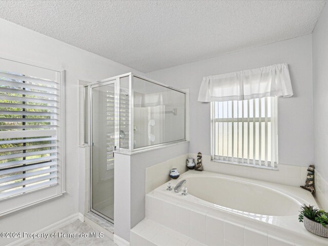 92 Randolph Ave, Spring Hill, FL 34606 - bathroom featuring a bath, a shower stall, and a textured ceiling