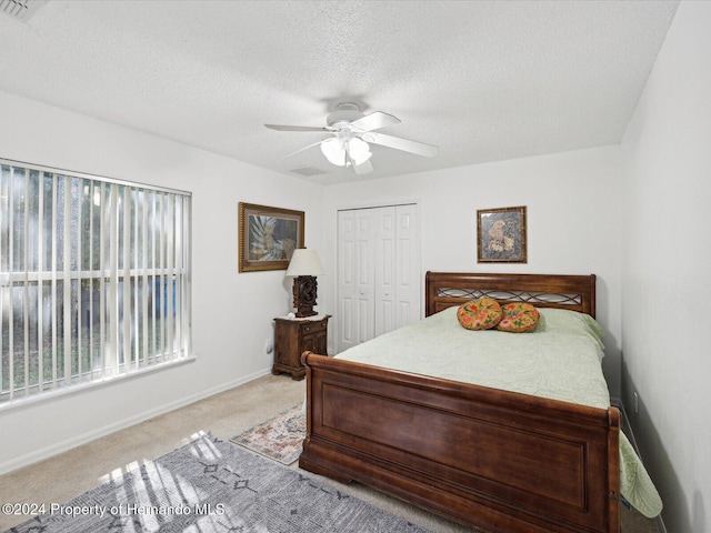 bedroom with light carpet, a textured ceiling, a closet, and ceiling fan