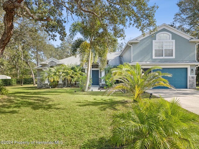 92 Randolph Ave, Spring Hill, FL 34606 - view of front of property with concrete driveway, a front yard, stucco siding, and a garage