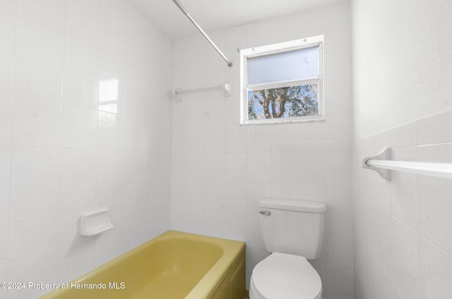 bathroom with toilet and tile walls