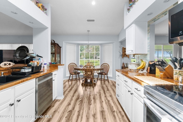 kitchen with white cabinetry, pendant lighting, light wood-type flooring, and appliances with stainless steel finishes