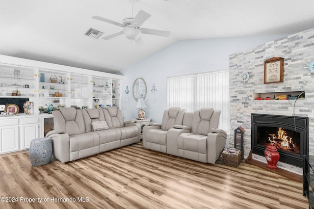 living room with a large fireplace, light hardwood / wood-style floors, vaulted ceiling, and ceiling fan