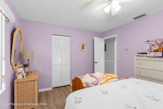 bedroom featuring ceiling fan, a closet, light hardwood / wood-style floors, and a textured ceiling