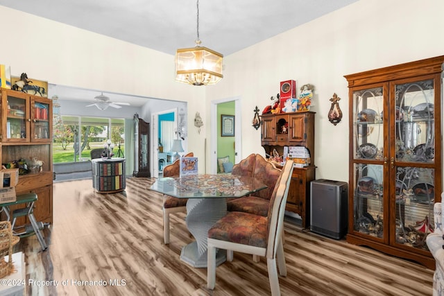 dining area featuring light hardwood / wood-style flooring and ceiling fan with notable chandelier