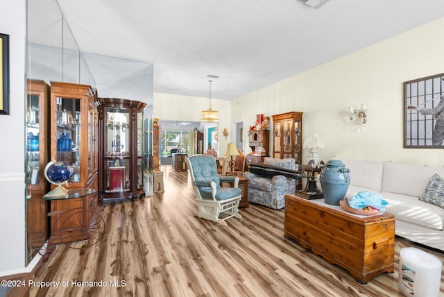 living room with a textured ceiling, hardwood / wood-style flooring, and vaulted ceiling