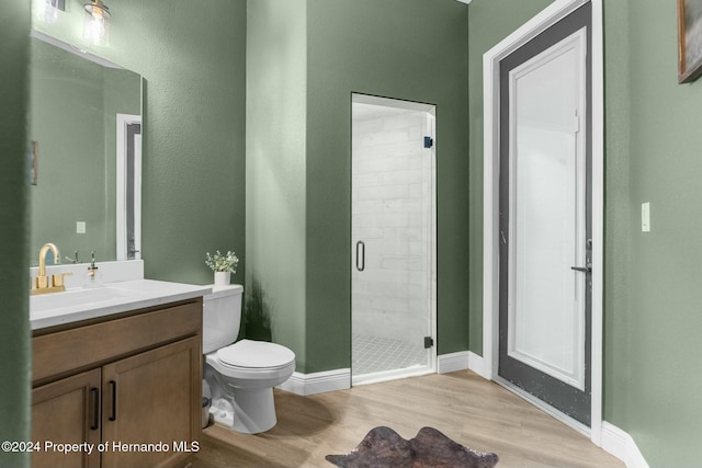 bathroom featuring hardwood / wood-style floors, vanity, toilet, and a shower with door