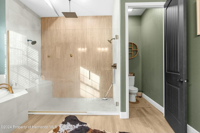 bathroom with toilet, wood-type flooring, and shower with separate bathtub