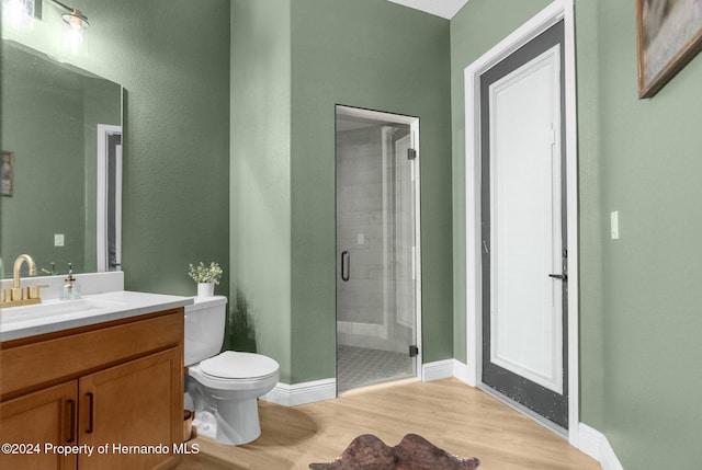 bathroom featuring hardwood / wood-style floors, vanity, toilet, and an enclosed shower