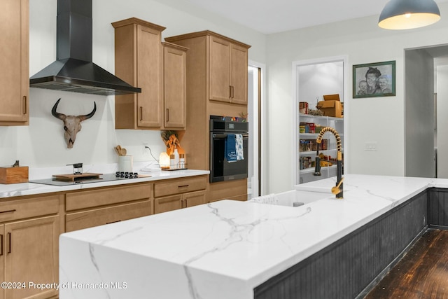 kitchen with a center island, black appliances, sink, wall chimney exhaust hood, and light stone counters