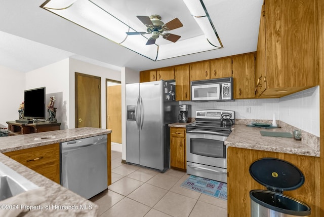 kitchen with appliances with stainless steel finishes, tasteful backsplash, ceiling fan, and light tile patterned flooring