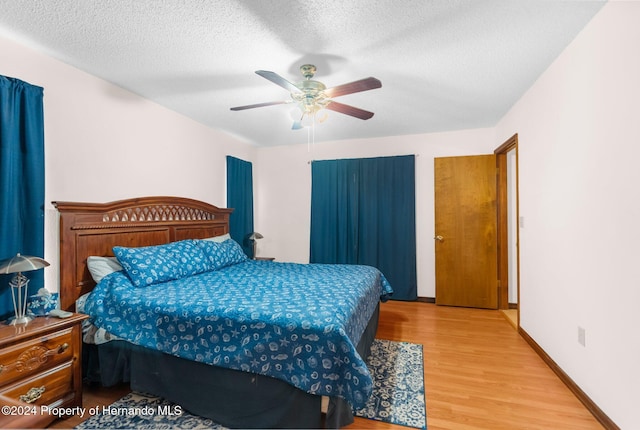 bedroom with ceiling fan, wood-type flooring, and a textured ceiling