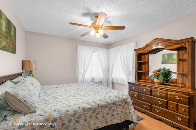 bedroom featuring hardwood / wood-style floors, ceiling fan, and a textured ceiling