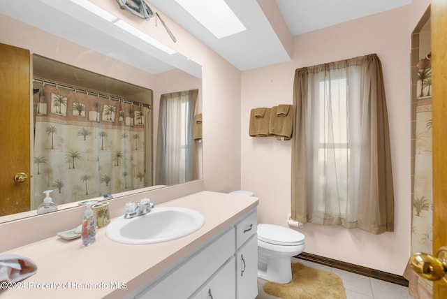 bathroom with tile patterned flooring, vanity, a skylight, and toilet