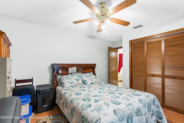 bedroom with ceiling fan, light wood-type flooring, a textured ceiling, and a closet