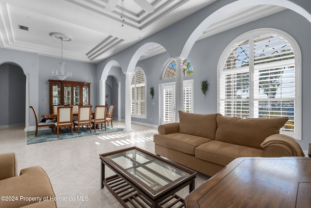 living room featuring ornate columns, light tile patterned floors, and ceiling fan with notable chandelier