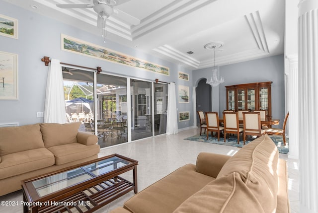 living room with ceiling fan with notable chandelier, a raised ceiling, and light tile patterned floors