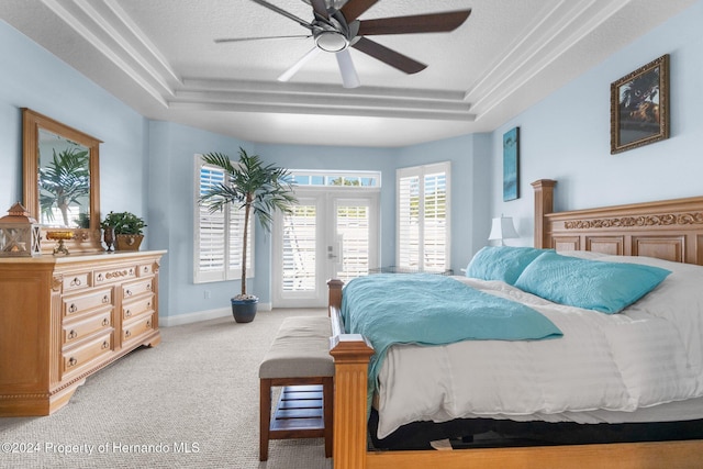 carpeted bedroom with ceiling fan, french doors, a textured ceiling, and a tray ceiling