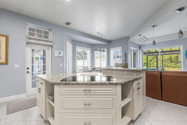 kitchen with pendant lighting, a kitchen island, white cabinets, and black electric cooktop