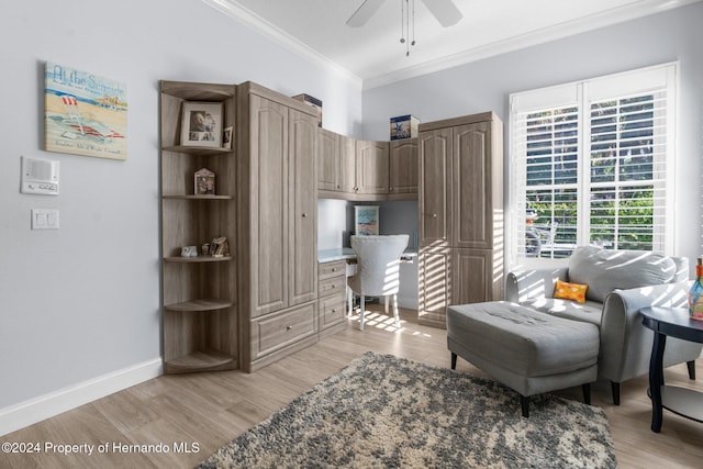 sitting room with ceiling fan, ornamental molding, built in desk, and light wood-type flooring