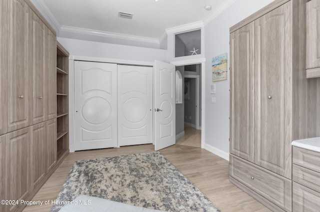 bedroom featuring a textured ceiling, light wood-type flooring, a closet, and ornamental molding