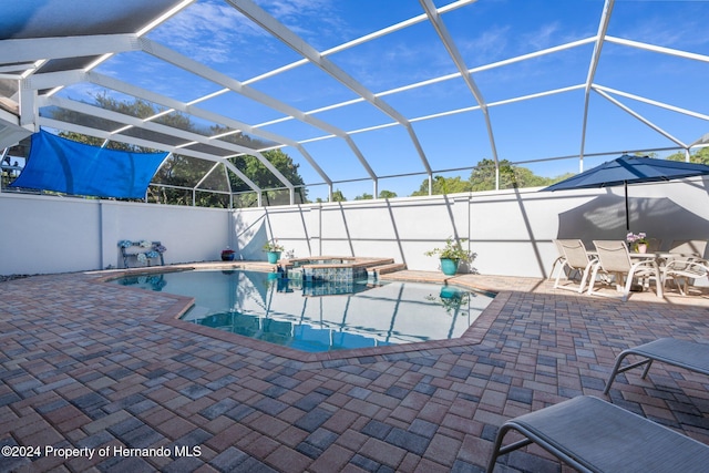 view of swimming pool with an in ground hot tub, a patio, and glass enclosure