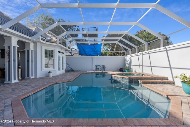 view of swimming pool featuring glass enclosure, a patio area, an in ground hot tub, and french doors