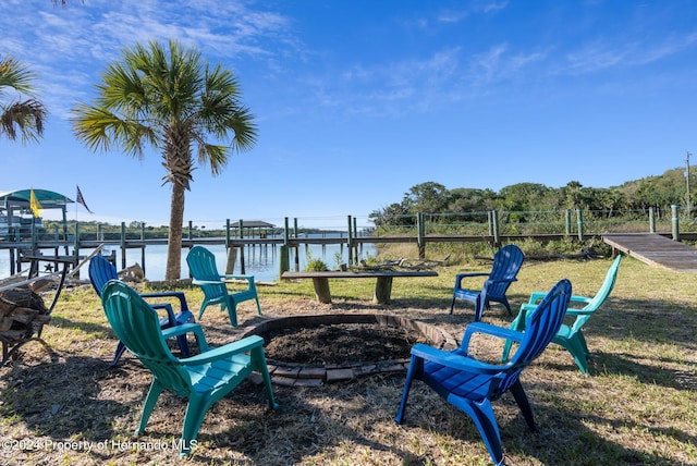 view of yard featuring a water view, a dock, and an outdoor fire pit