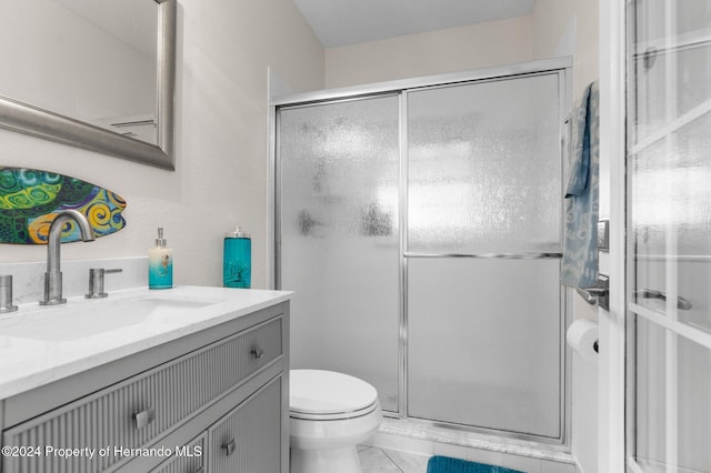 bathroom featuring toilet, vanity, tile patterned floors, and an enclosed shower