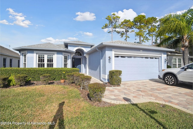 ranch-style house with a garage and a front lawn